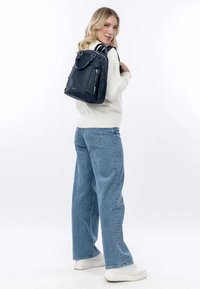 Zaino navy con doppie maniglie superiori e spallacci regolabili, materiale sintetico liscio, tasca frontale con zip e dettagli hardware argentati.