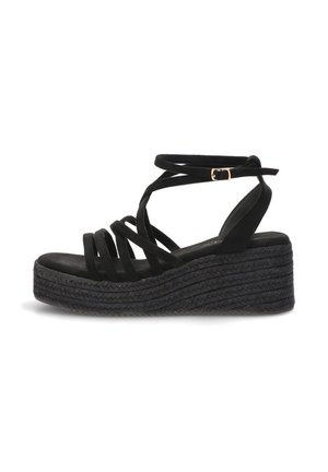 Sandalia de cuña plataforma negra con múltiples tiras delanteras, correa para envolver el tobillo y cierre de hebilla dorada.