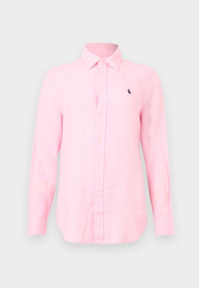 Chemise rose à manches longues, boutonnée, avec col et petit logo foncé brodé sur la poitrine gauche sur un fond clair.