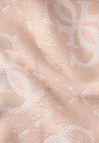 Tissu rose doux présentant un motif de logos blancs entrelacés. La texture est lisse avec une apparence légèrement tissée.