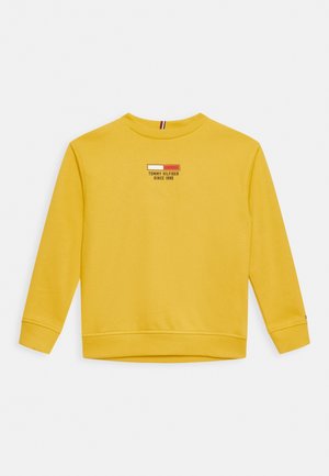 Sudadera amarilla de manga larga con puños y dobladillo acanalados, con el logo de Tommy Hilfiger y el texto "Desde 1985" en el pecho.