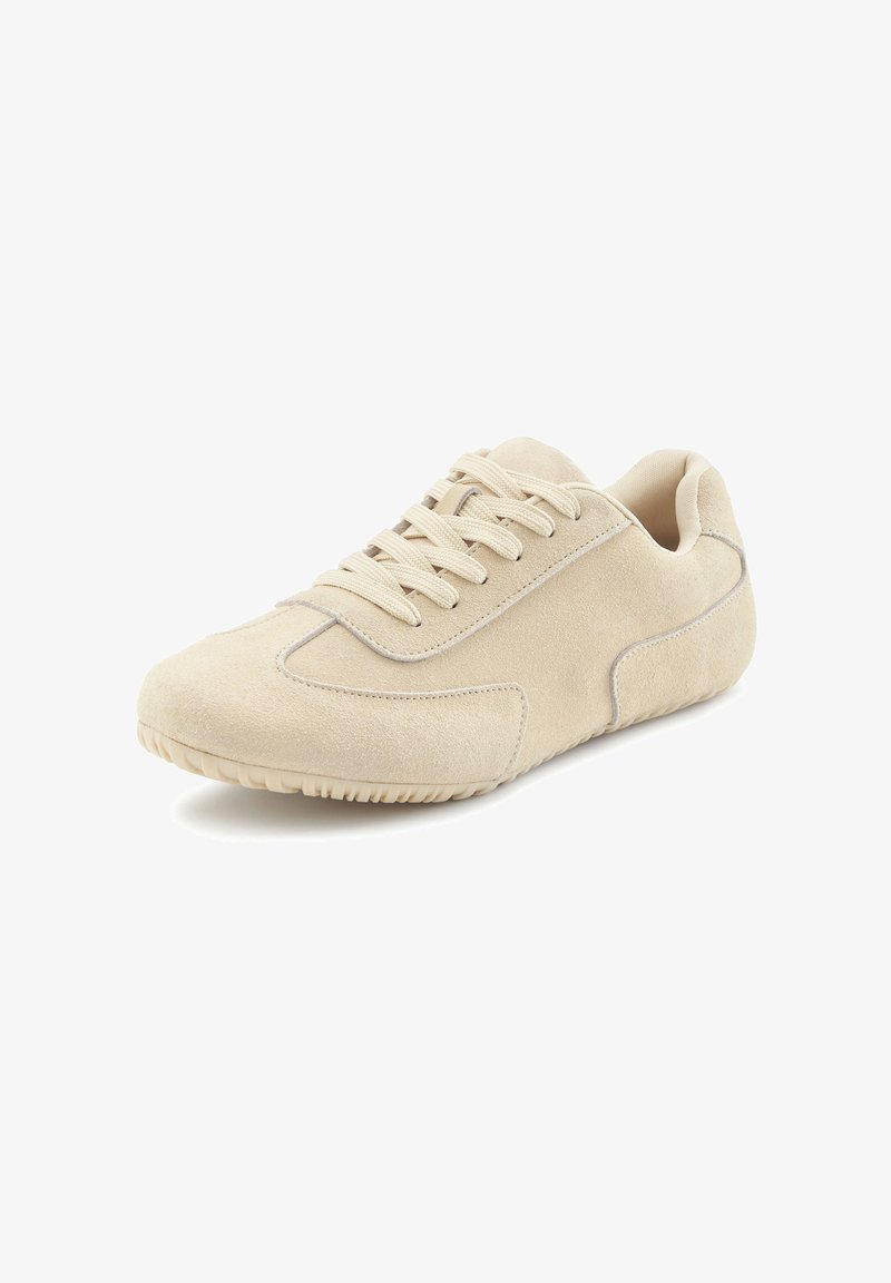 Beige suede sneakers with a rounded toe, laces on the front, and textured sole. Smooth sides with subtle stitching accents.