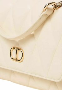Borsa a tracolla in pelle trapuntata color crema con chiusura a logo in tonalità oro e dettaglio a catena. Presenta una texture liscia e un motivo geometrico sulla superficie.
