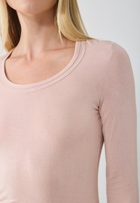 Rosa Langarmtop mit rundem Ausschnitt; aus weichem, glattem Stoff gefertigt, mit tailliertem Schnitt und subtiler Glanz.