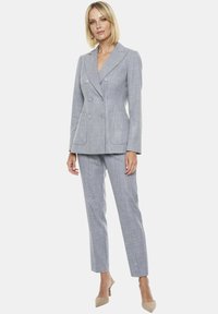 Szary żakiet podwójnie zapięty w paski z klapami, dwoma przednimi kieszeniami i dopasowanymi spodniami o slim fit. Dodaje eleganckiego wyglądu.