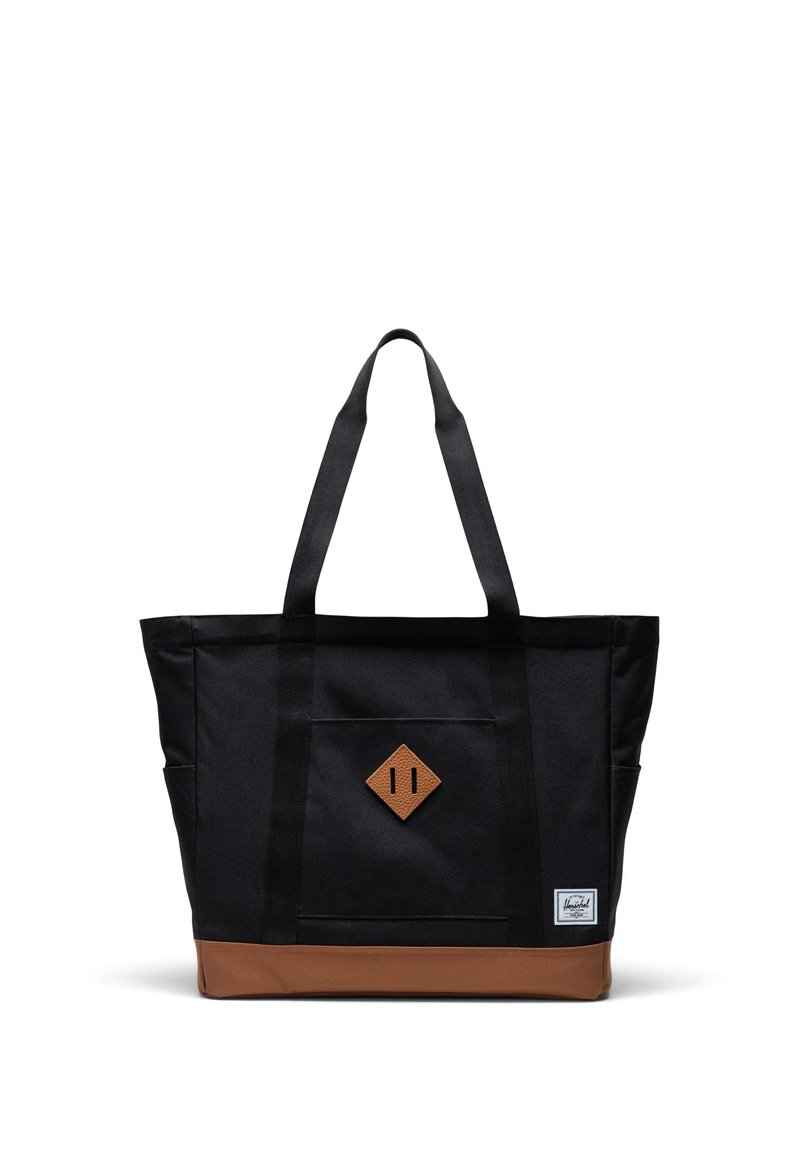 Svart tygväska med brun bottenaccent, med två stabila handtag och en diamantformad läderlapp på framsidan.