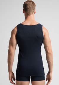 Námořnická modrá ribbená tílko se širokými ramínky, přiléhavý střih a minimalistický styl, nošené s odpovídajícími šortkami.