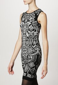 Abito aderente a stampa bianco e nero con design senza maniche, caratterizzato da intricati motivi floreali e geometrici. Texture liscia.