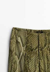Pantalons en faux cuir de serpent vert avec un design texturé, présentant une finition lisse et un subtil éclat. Les coutures visibles accentuent le look ajusté.