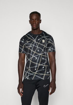 Maglietta nera a maniche corte con motivo galattico caratterizzato da linee e punti chiari, logo Nike dorato ed emblema del Chelsea.