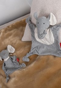 Two gray elephant plush toys, one larger with light fabric ears and a knot design, and a smaller companion, both on a soft brown surface.