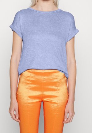 Lichtblauw T-shirt met korte mouwen en een ronde hals, gecombineerd met glanzende oranje broek met een textuur en golvend patroon.