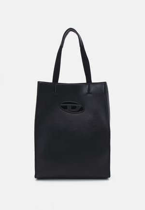 Sac fourre-tout noir en cuir lisse, avec deux poignées courtes, un détail de logo ovale et un design minimaliste sans fermetures visibles.