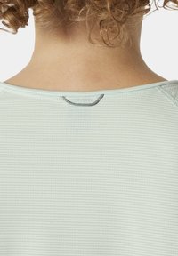 Světle zelený sportovní top s texturovaným, žebrovaným vzorem. Má kulatý výstřih a malý šedý akcent na zadní straně.