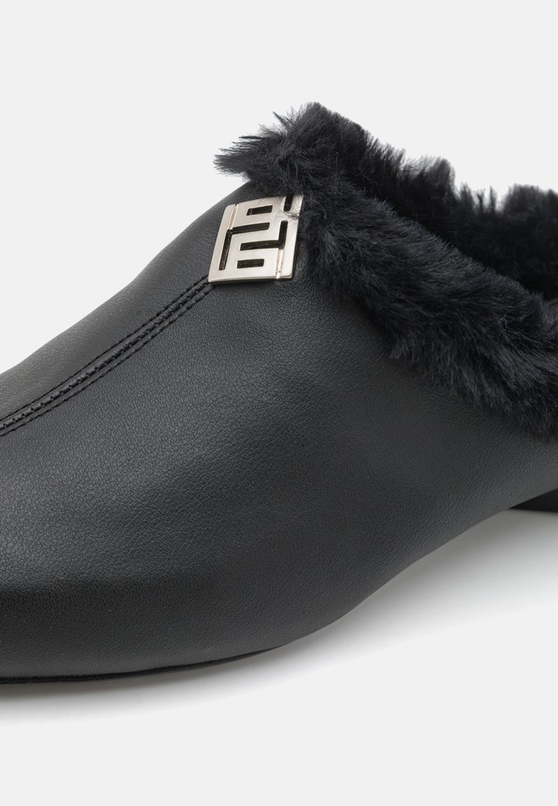 Black leather slip-on shoe with a plush black fur lining and a silver logo accent on the side. Smooth texture and rounded shape.