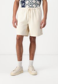 Beige Cordshorts mit einem elastischen Bund und Kordelzug. Sie verfügen über eine strukturierte Oberfläche und enden knapp über dem Knie.