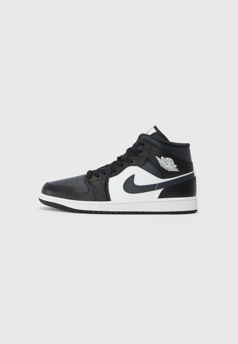 Vysoké tenisky s černou a bílou kůží, mají perforovaný špičkový kryt, kulaté tkaničky a šedé logo Nike na boku.
