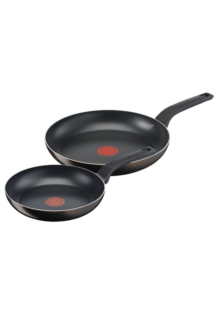 Deux poêles antiadhésives, une grande et une petite. Les deux ont un extérieur noir lisse, un intérieur texturé et des cercles d'induction rouges.