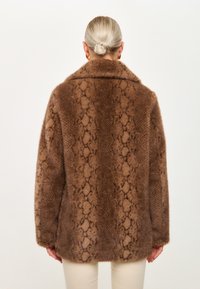 Brauner Kunstfellmantel mit Schlangenhautmuster, ausgestattet mit einem breiten Kragen und lockerer Passform. Weiche Textur mit einem subtilen Glanz, keine sichtbaren Hardwareelemente.