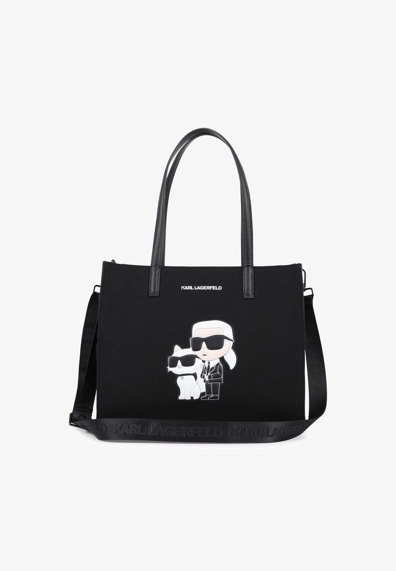 Μαύρη τσάντα ώμου από καμβά με δύο καρτούν φιγούρες στην πρόσοψη. Διαθέτει μαύρες δερμάτινες λαβές και ρυθμιζόμενο λουρί. Εμφανίζεται λογότυπο.