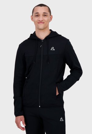 Zwarte ritshoodie van zacht materiaal met een kangoeroezak, verstelbare trekkoorden en logo-accent op de borst.