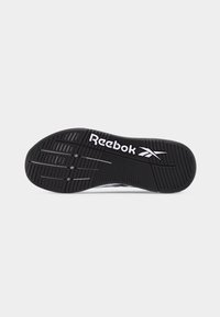 Μαύρη σόλα παπουτσιού Reebok με υφή λαβής και λευκό λογότυπο Reebok και σύμβολο βέλους σε απλό φόντο.