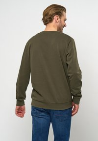 Olijfgroene sweatshirt met lange mouwen en ribgebreide manchetten, voorzien van een ronde hals en een zachte, gestructureerde afwerking. Achteraanzicht weergegeven.