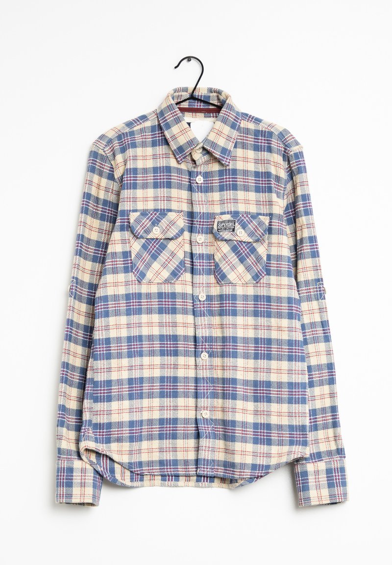 Camisa de cuadros con botones en la parte delantera, dos bolsillos en el pecho y una etiqueta en el bolsillo izquierdo. Patrón de cuadros en azul, crema y rojo; mangas largas.