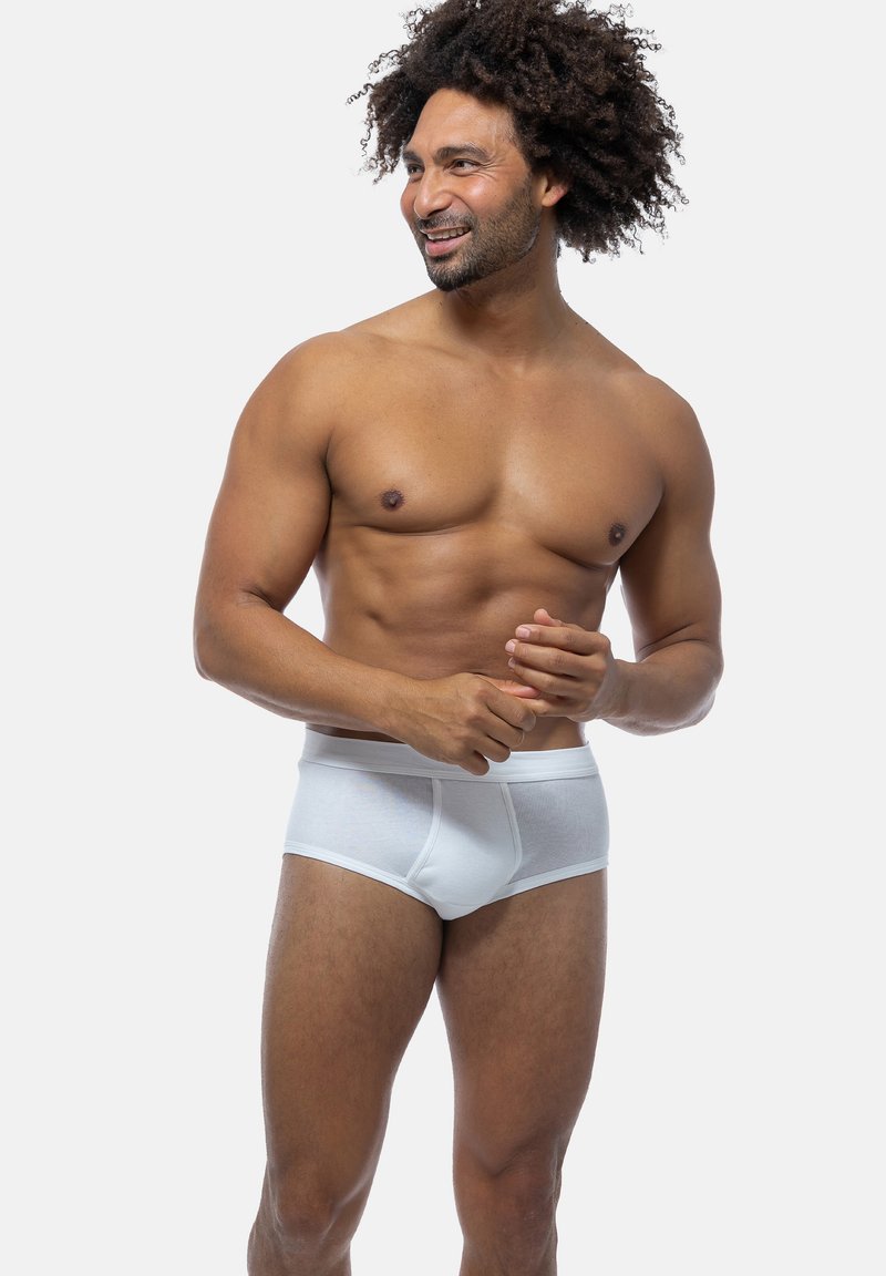 Weißer Baumwoll-Boxerslip mit enganliegendem Schnitt, präsentiert sich mit einer glatten Textur und einem klassischen Bunddesign. Das Modell posiert lässig.