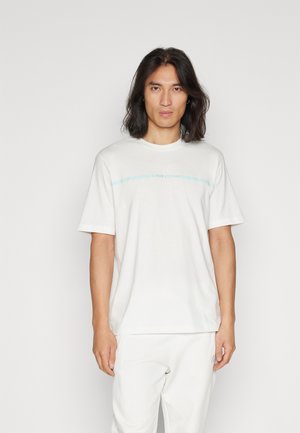 T-shirt bianca in cotone con maniche corte, scollo rotondo e logo azzurro "Armani Exchange" stampato sul petto.