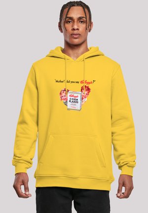 Gelber Kapuzenpullover mit einer Fronttasche, die ein Grafikmotiv von Vintage-Kindern und den Schriftzug "Kellogg’s Corn Flakes" in Rot und Weiß zeigt.