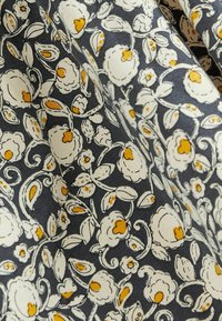 Tissu noir avec un motif floral blanc et jaune comprenant des fleurs et des feuilles stylisées réparties sur toute la surface.