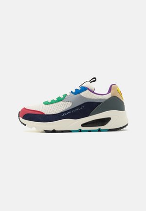 Zapatillas deportivas que combinan materiales como malla y ante, en blanco, azul marino, rojo, verde y púrpura, con detalles texturizados y el logotipo.