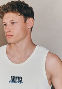 Canotta bianca senza maniche con motivo testurizzato, con "PROVENCE" ricamato in blu sul petto. Design semplice con scollo rotondo.