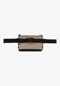 Sac à bandoulière en tissu beige avec des accents noirs, de forme rectangulaire, sangle noire réglable et fermeture éclair durable.