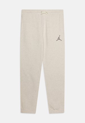 Pantalones de chándal gris claro con cintura ajustable por cordón, presentan un pequeño logo negro de Jumpman cerca del muslo izquierdo. Material de algodón suave y texturizado.