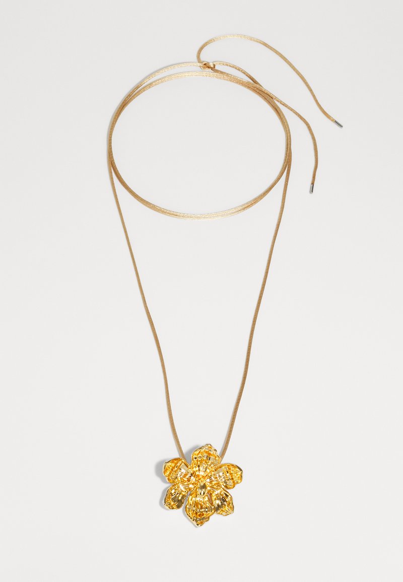 Guld blomst vedhæng på et tyndt brunt snorhalskæde. Vedhænget har teksturerede kronblade og en central detalje, der fremhæver dets blomsterdesign.