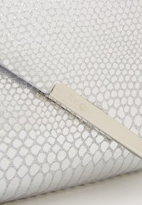 Vit clutchväska med ormskinnsmönster och metalliska accenter, slät yta och en silverfärgad stängning graverad med "Mascara."