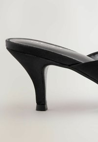 Schwarze hochhackige Sandale mit einem schlanken Design, einem glatten Obermaterial aus Stoff und einem schlanken, leicht gebogenen Absatz.