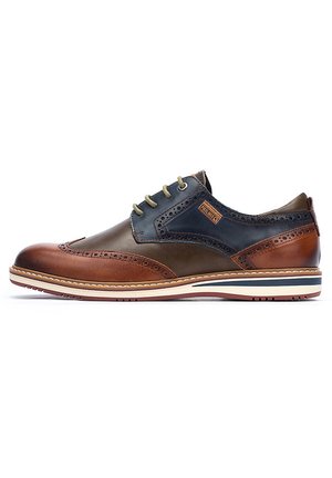 Zapato de vestir de cuero con una combinación de colores marrón y azul oscuro. Presenta detalles de brogue, cordones beige y un diseño de suela en capas.