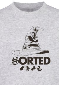 Gray cotton T-shirt featuring a graphic of a worn wizard hat above the word "SORTED" with four house icons below.