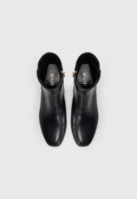 Czarne skórzane botki za kostkę o eleganckim designie, szpiczastym nosku i złotych akcentach. Gładka faktura, pełna cholewka i płaska podeszwa.