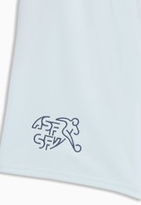 Tissu blanc avec un petit logo brodé bleu marine représentant un joueur de football stylisé en train de frapper un ballon, avec les lettres ASF SFV.
