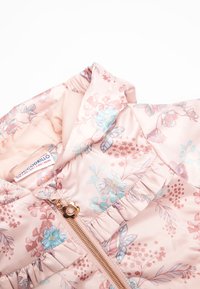 Kurtka puchowa we wzory kwiatowe w pastelowym różu, z falbaną i złotym zamkiem błyskawicznym. Wykonana z gładkiego materiału z miękką podszewką.