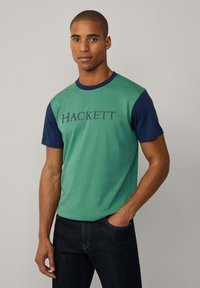 Camiseta de manga corta verde y azul marino con el logo "HACKETT" en azul oscuro. Material de algodón con un diseño clásico de cuello redondo.