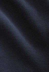 Dunkelblauer Stoff mit einer strukturierten Webart, die subtile Wellen und Tiefe zeigt, geeignet für verschiedene Textilanwendungen.