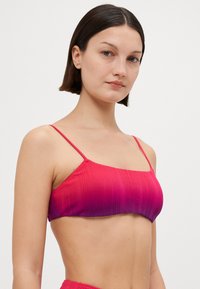 Rosa gradientbralette med tunna axelband. Har texturerad ribbning, fyrkantig halsringning och en figurnära silhuett.