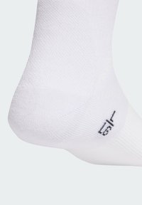 White athletic sock showing a textured pattern, featuring reinforced heel, with a small black label near the ankle indicating size 1/2.