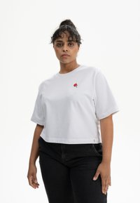 Witte cropped t-shirt van katoen, met een klein rood paddenstoelenlogo op de borst. Voorzien van korte mouwen en een relaxte pasvorm.
