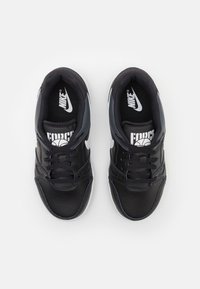 Ein Paar schwarze Nike Sneakers mit weißen Swoosh-Logos und "Force"-Branding auf der Zunge, von oben auf einem weißen Hintergrund dargestellt.